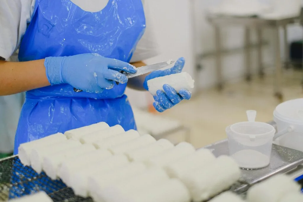 pexels-photo-5953687-5953687 Worker processing cheese with gloves in a sterile dairy factory environment.